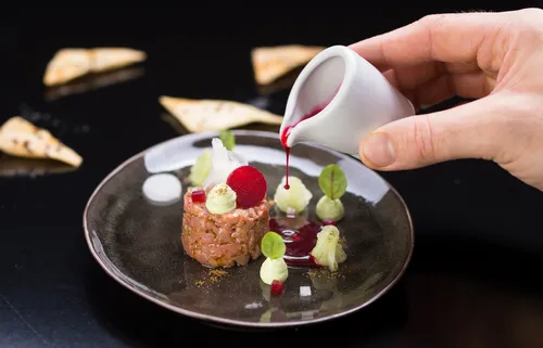 Gourmet-Rindertatar mit Rote-Bete-Sauce auf elegantem schwarzen Teller