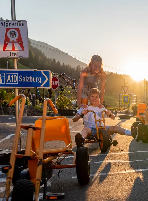 Kinder spielen mit Tretkarts an einem sonnigen Tag im Freien bei Salzburg
