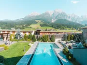 Outdoor swimming pool with sun loungers at hotel resort overlooking alpine mountains