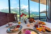 Deluxe breakfast with fruit, pastries and cold cuts overlooking alpine mountain scenery