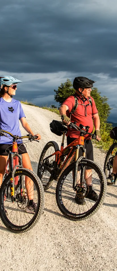 Group of cyclists on mountain trail enjoying scenic landscape with cloudy sky