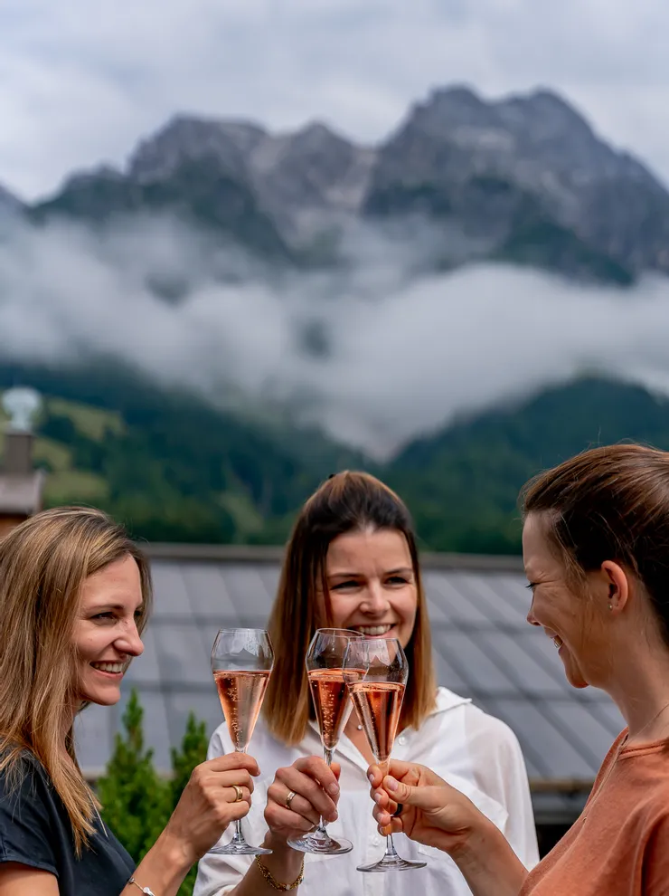 Frauen stoßen mit Rosé-Champagner draußen in den Bergen an