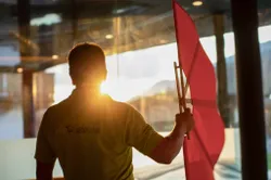Mann mit roter Spa-Fahne am Innenpool bei Sonnenuntergang durch das Fenster