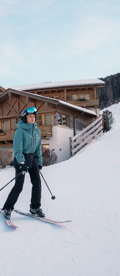 Skier on snowy slope in front of alpine ski resort with wooden chalet buildings