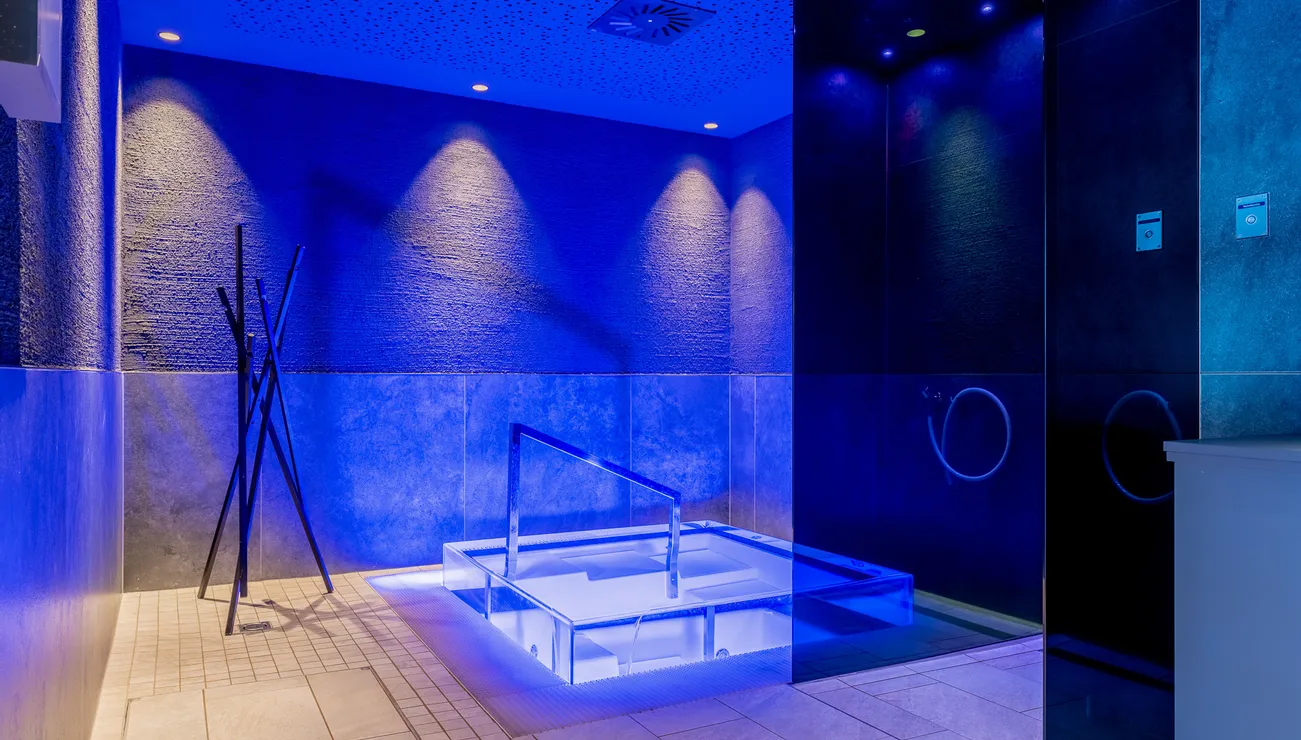 Modernes Spa mit beleuchtetem Tauchbecken und blauer Ambientebeleuchtung