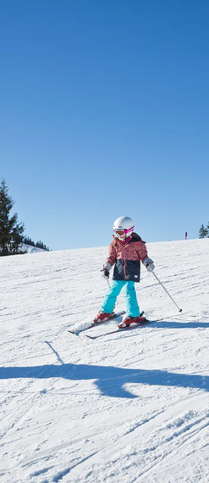 Family skiing together on a sunny slope with children learning to ski