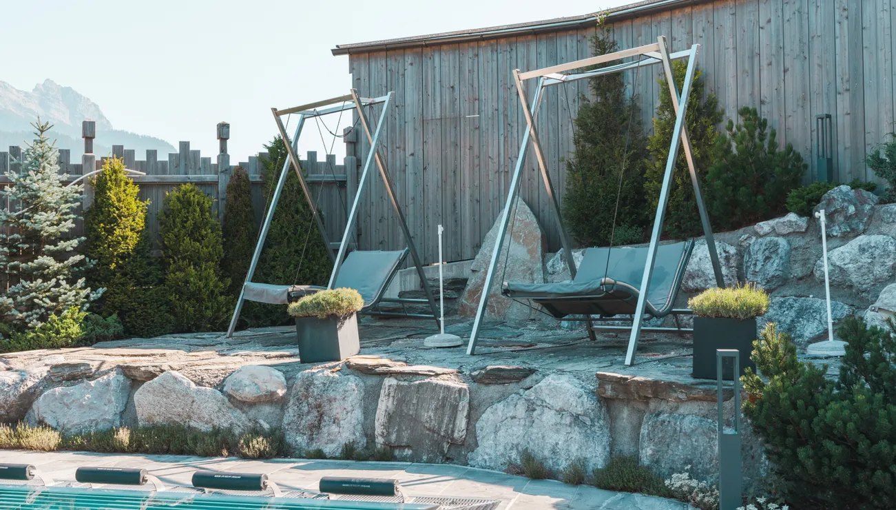 Moderne Outdoor-Schaukeln am Pool mit Holzzaun und Bergblick