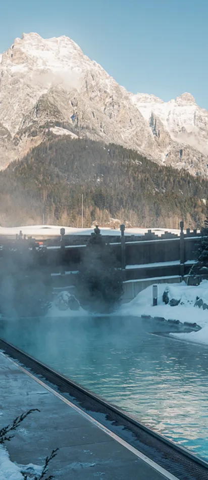 Outdoor thermal pool in snowy alpine resort with mountain view